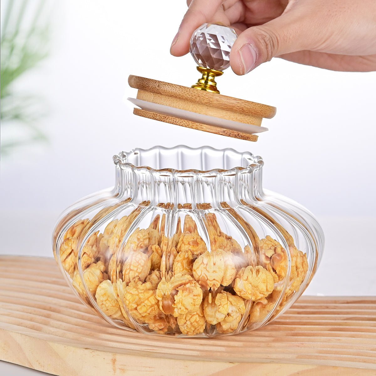 Clear glass jar with wooden lid filled with snacks on a wooden surface