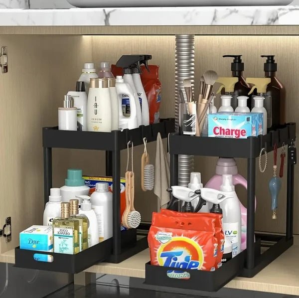 Under-sink organizer with cleaning supplies and toiletries on a kitchen counter.