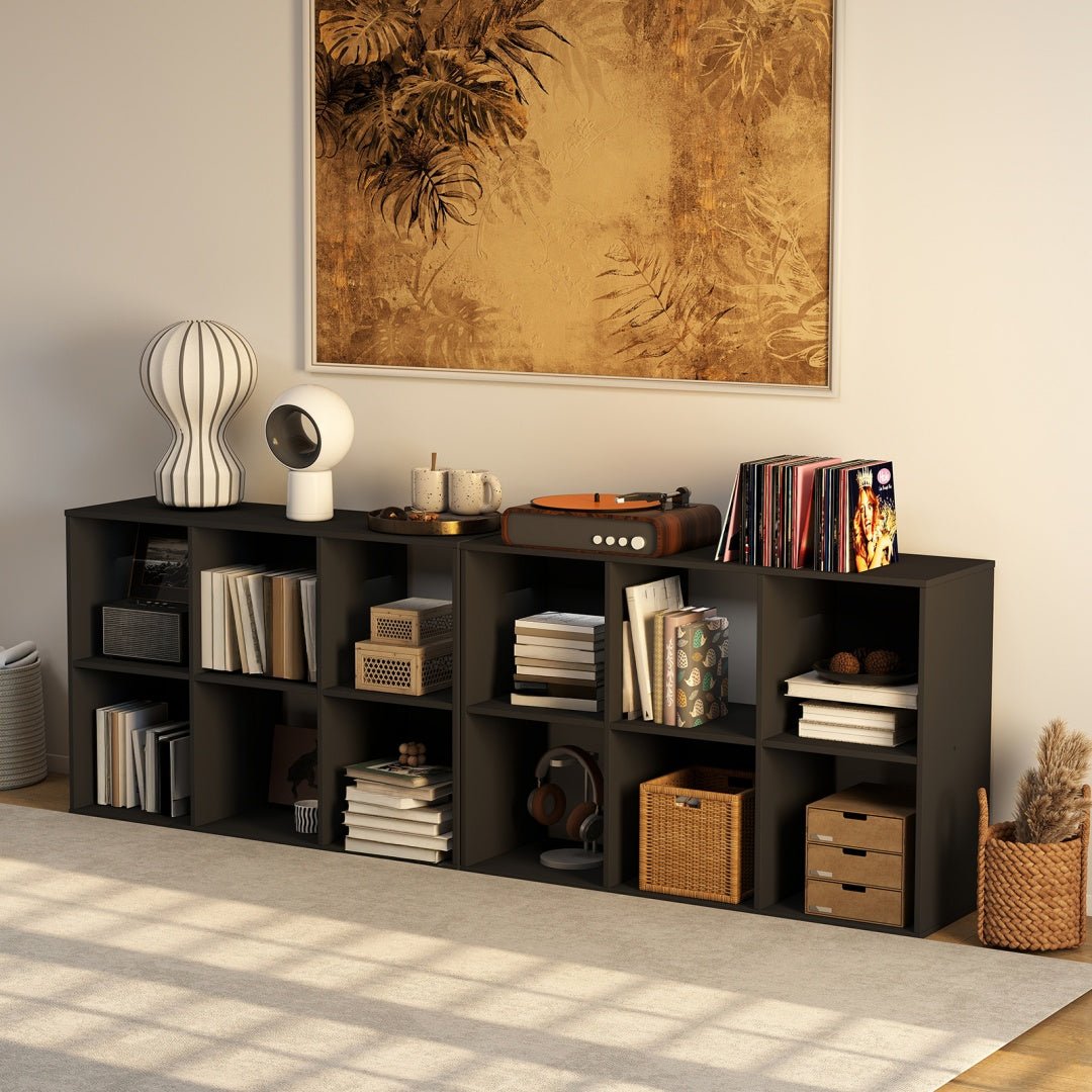 Black bookshelf with various items in a room with a painting on the wall.