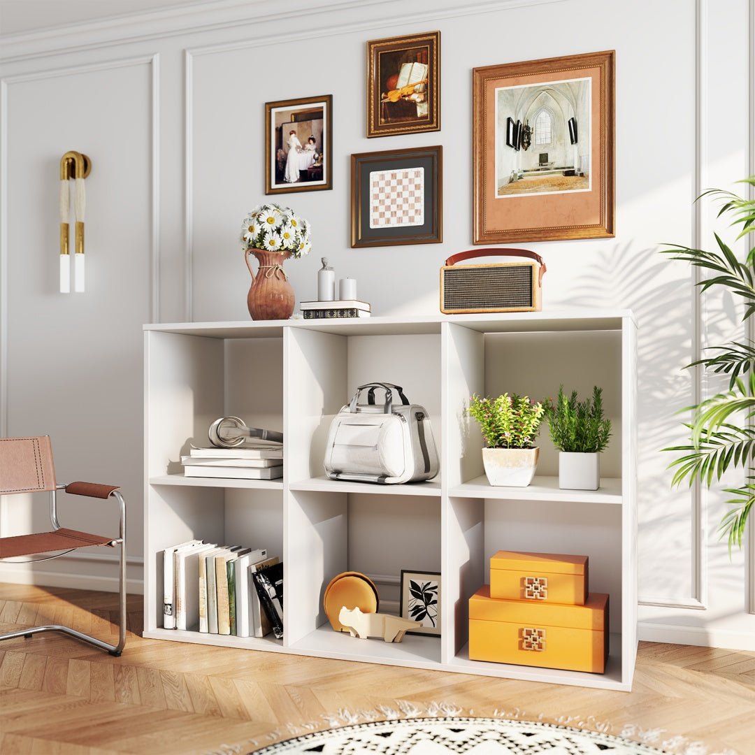 White bookshelf with decorative items in a room with a chair and wall art.