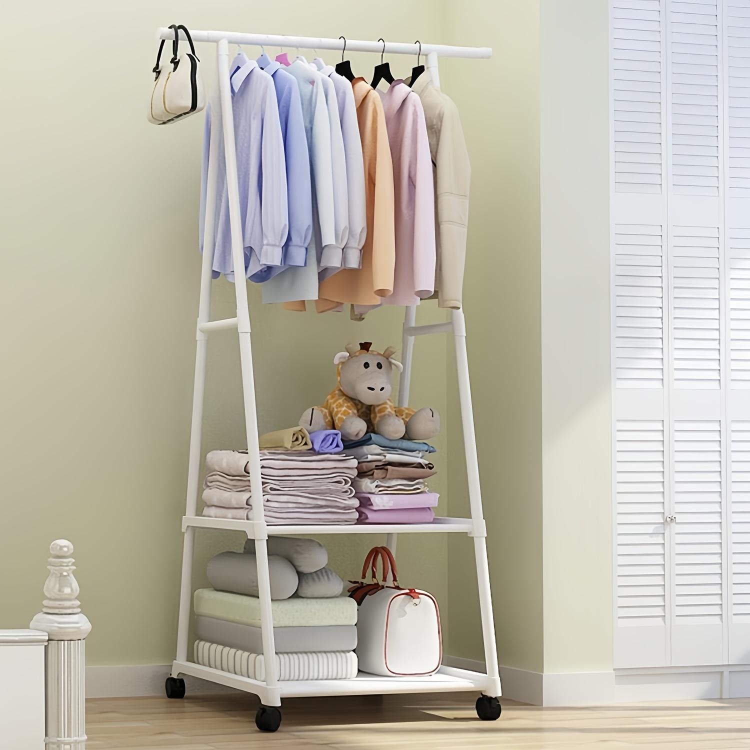 White clothing rack with clothes, toys, and bags against a light green wall.