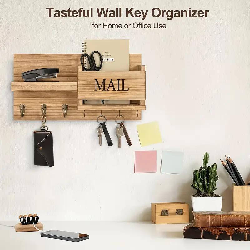 Wooden wall key organizer with hooks and compartments on a white wall.
