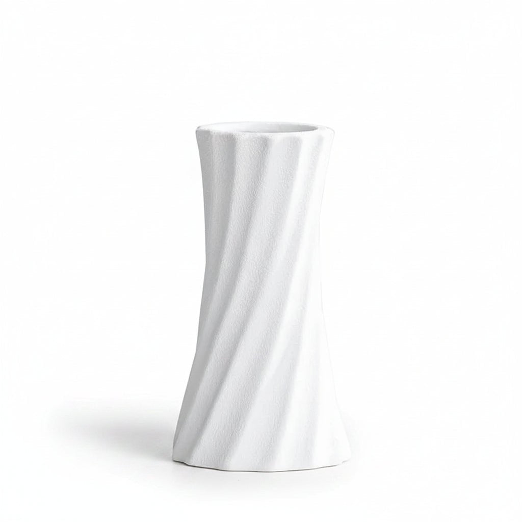 A white textured ceramic vase with a twisted spiral design, shown on a light gray surface with a soft shadow. Text in the upper left corner reads '6.