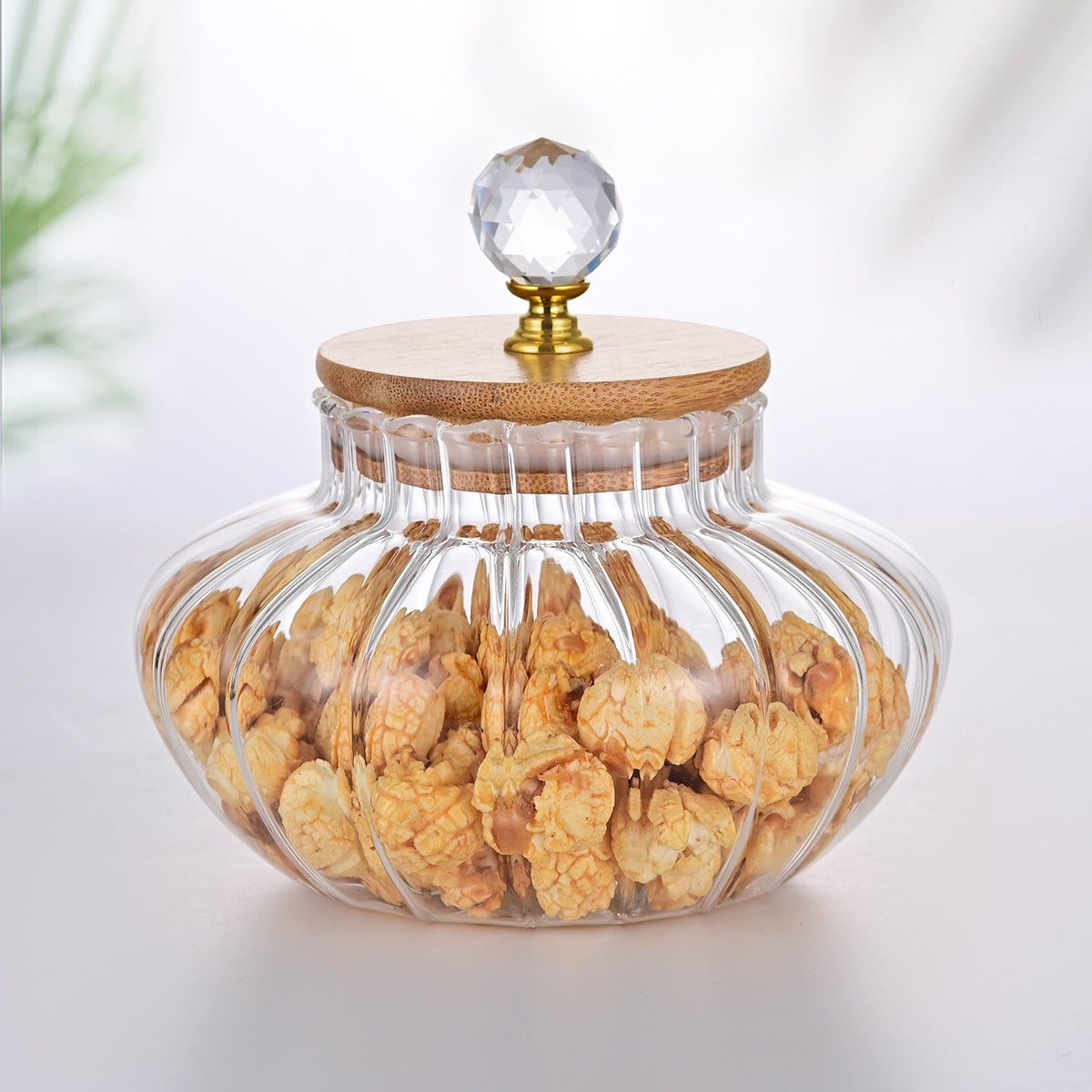 Glass jar with wooden lid and crystal knob filled with snacks on a white background