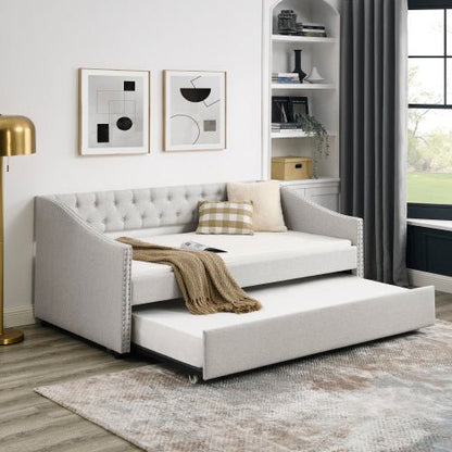 Gray tufted sofa bed with pull-out mechanism in a room setting.