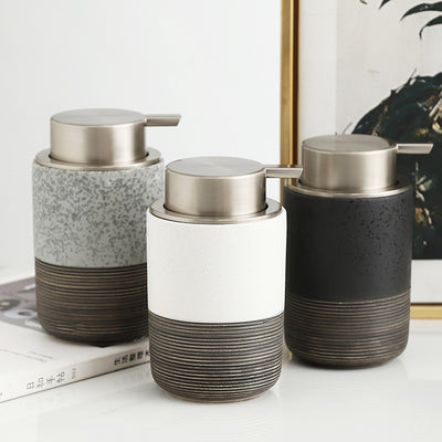 Three ceramic soap dispensers with metallic pumps on a white surface.