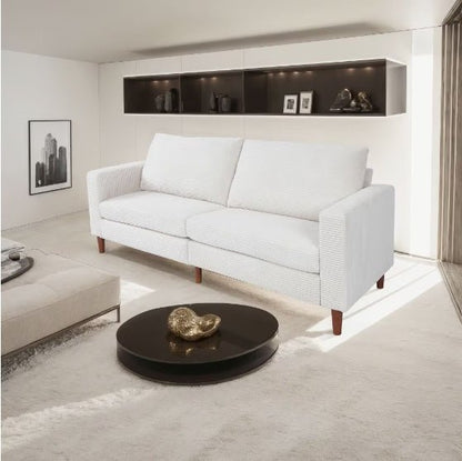 White sofa in a modern living room with a round dark coffee table.
