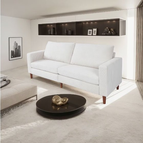White sofa in a modern living room with a round dark coffee table.