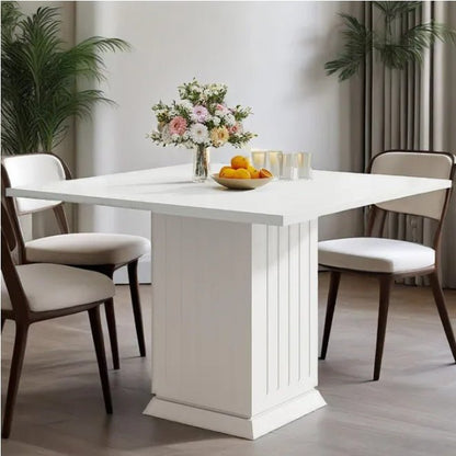 White dining table with chairs and a floral arrangement in a room.