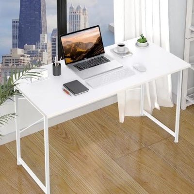 White office desk with laptop, phone, and coffee cup in a room with cityscape view.
