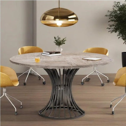 Round dining table with a unique metal base in a modern room with yellow chairs and a gold pendant light.