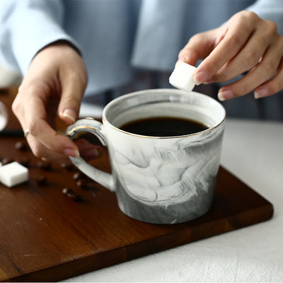 Person adding a white cube to a cup of coffee on a wooden tray.