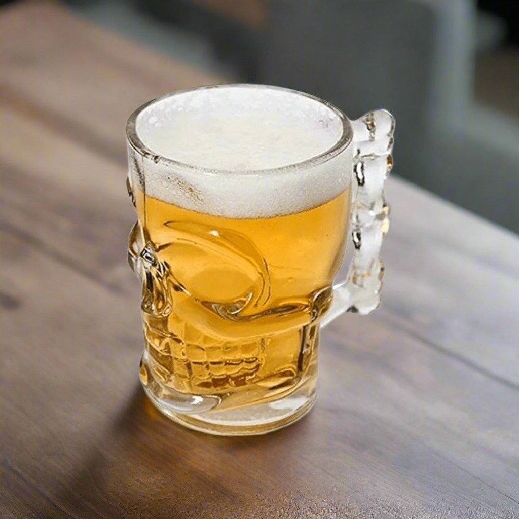 Clear glass skull-handled beer mug filled with frothy beer on a wooden table.