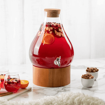 Beverage drink dispenser with clear glass design showcasing vibrant red punch with fruits on a wooden stand.