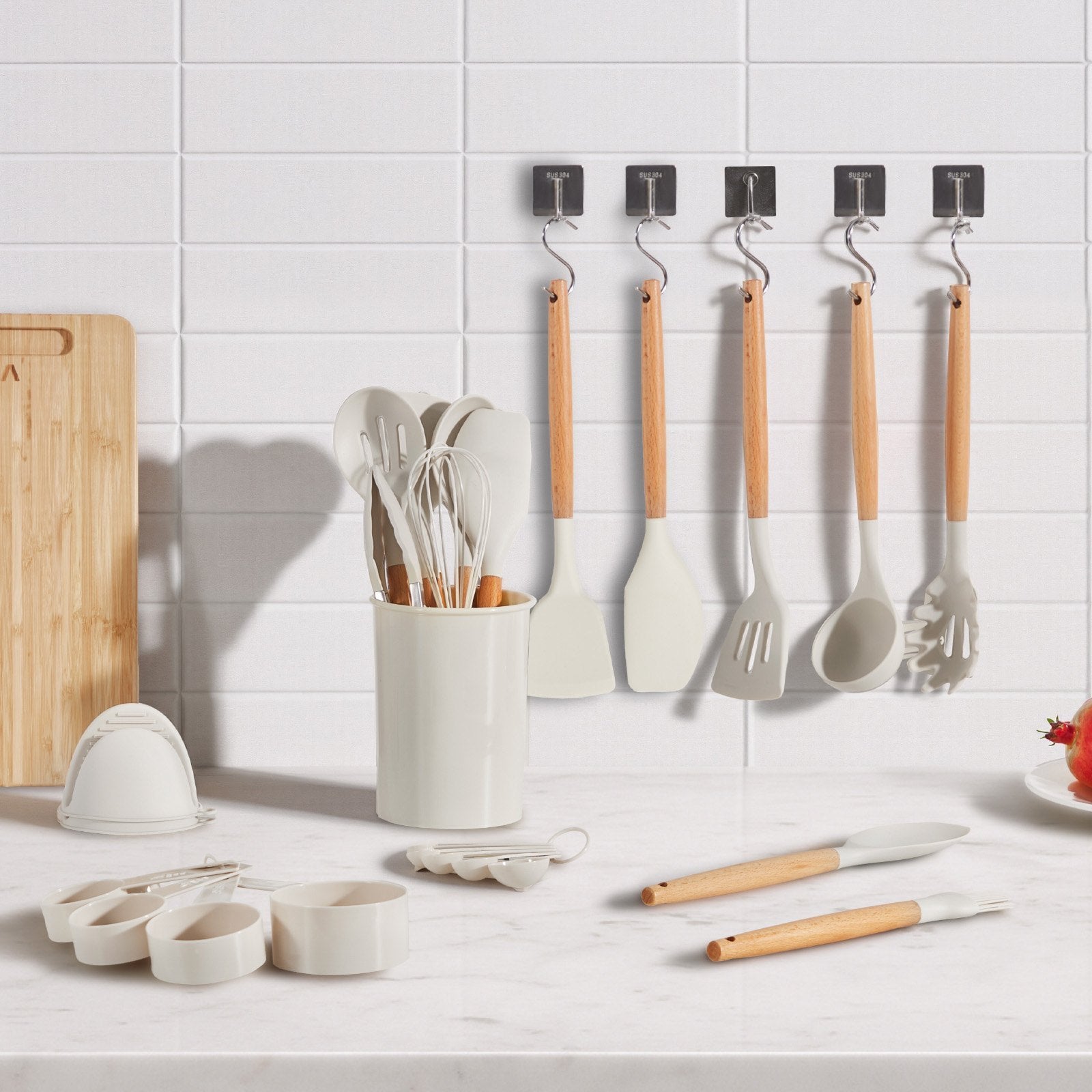Kitchen utensils including spatulas and measuring cups on a white countertop with a tiled wall background.