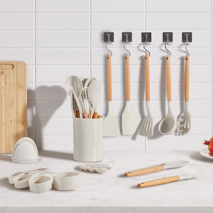 Kitchen utensils including spatulas and measuring cups on a white countertop with a tiled wall background.