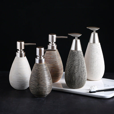 Set of ceramic soap dispensers with metallic pumps on a dark background