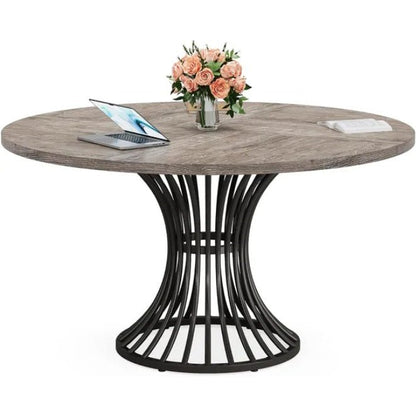 Round wooden table with black metal base, laptop, and flowers on a white background