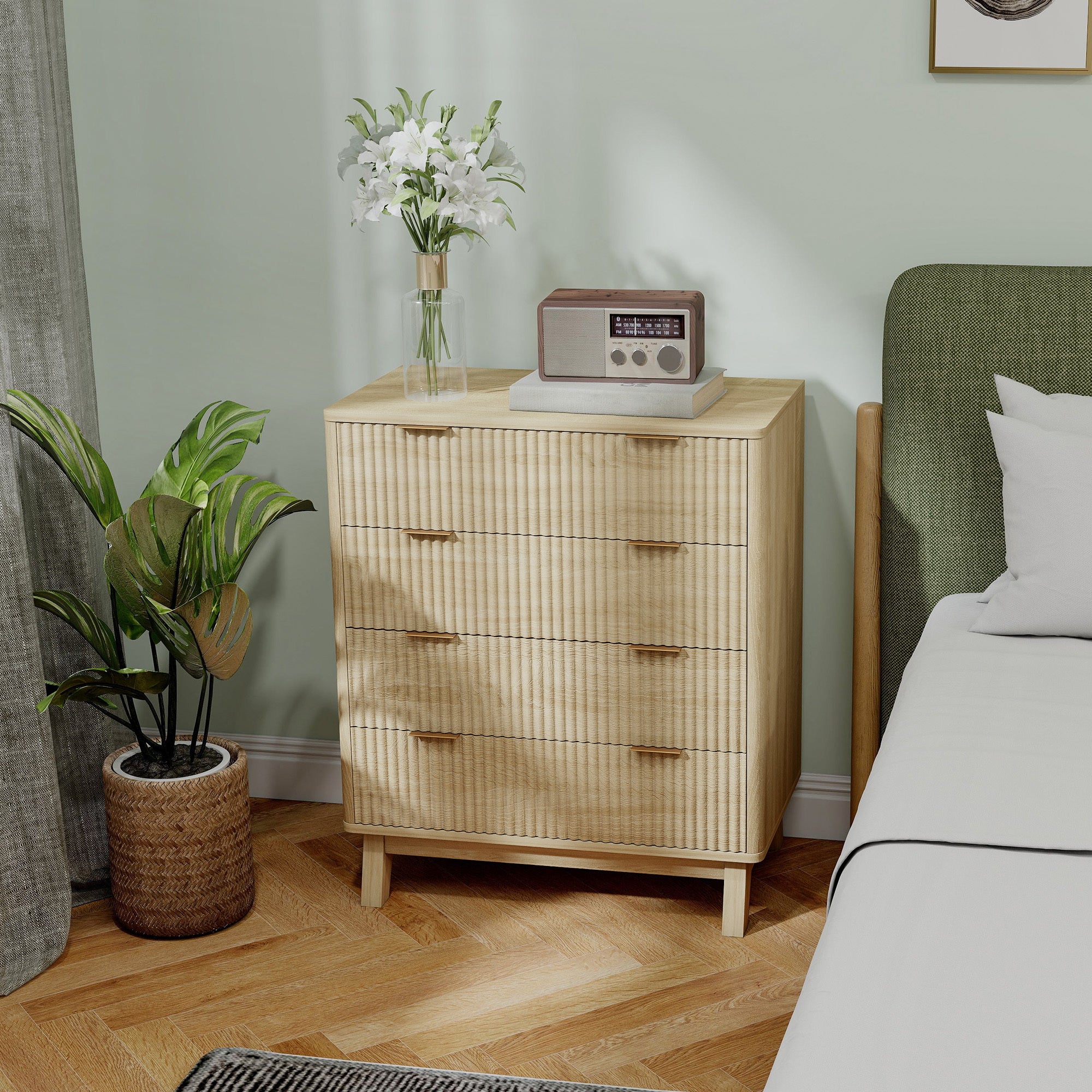 Wooden dresser with a radio and flowers in a room with a bed and plant.