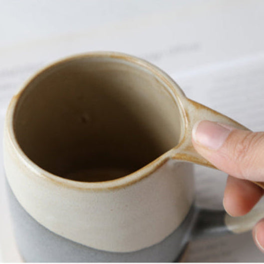Hand holding a ceramic measuring cup with dark liquid on a white background