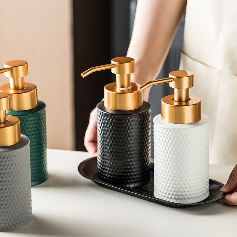 Set of decorative soap dispensers with gold pumps on a tray.