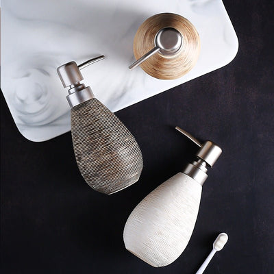 Two ceramic soap dispensers with metallic pumps on a dark surface.
