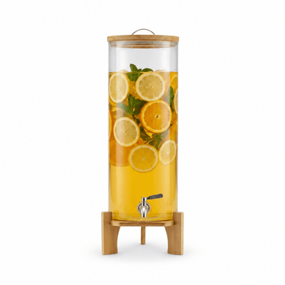 Front view of a glass drink dispenser with citrus slices, stainless steel spigot, and wood stand
