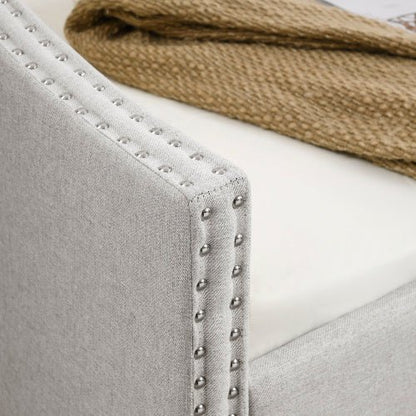 Close-up of a gray upholstered chair with studded detailing and a brown fabric item on top.
