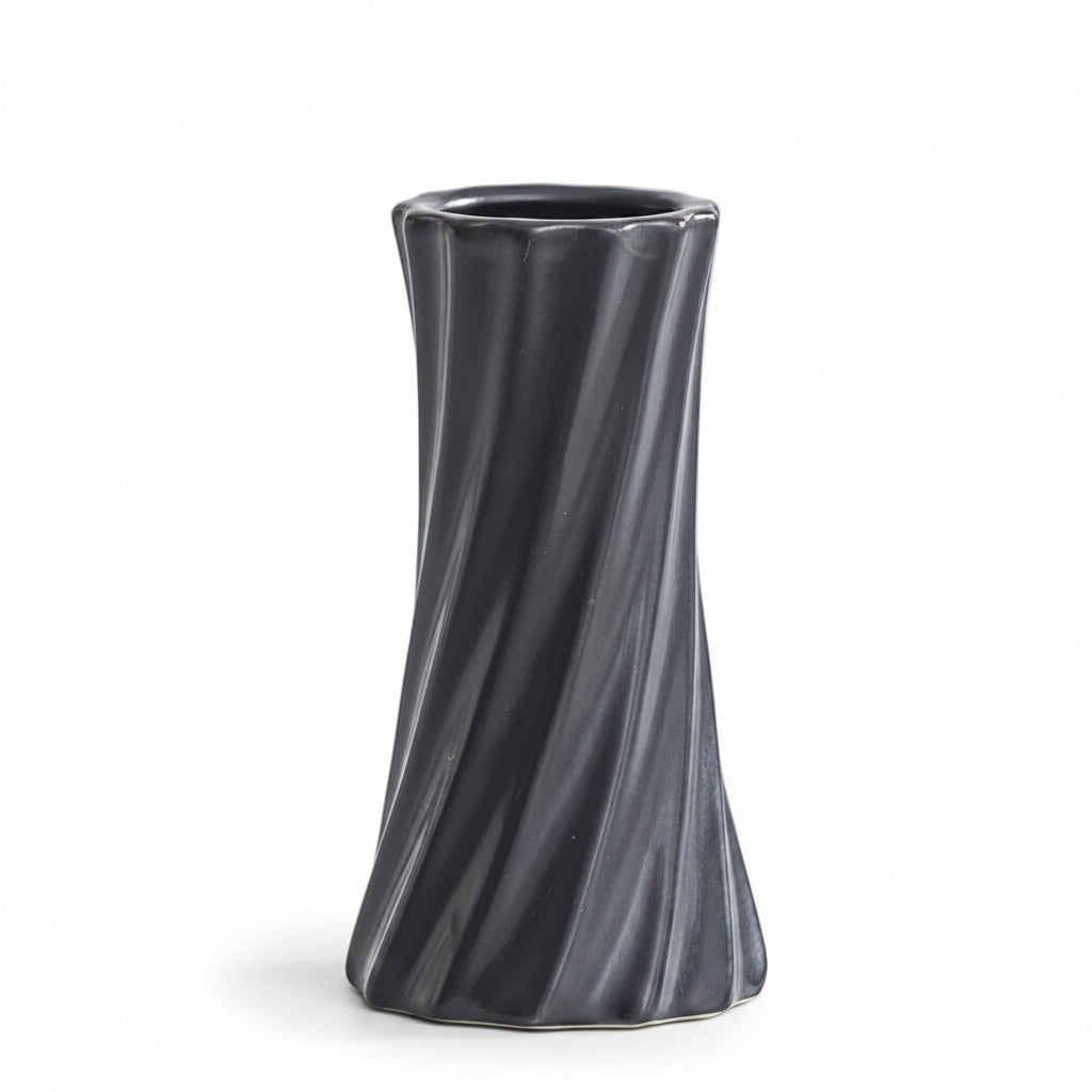 A dark gray, twisted ceramic vase with a flared rim, shown on a light gray surface with a white background. Text in the upper left corner displays the dimensions: '6.