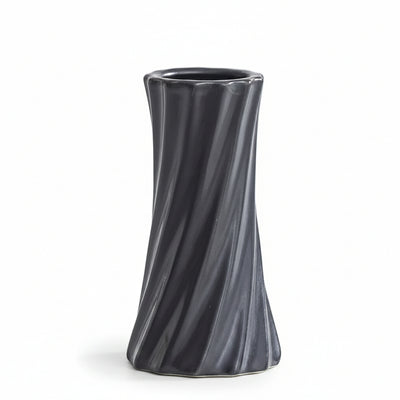 A dark gray, twisted ceramic vase with a flared rim, shown on a light gray surface with a white background. Text in the upper left corner displays the dimensions: '6.