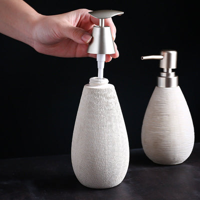 White textured soap dispenser with silver pump on a black background