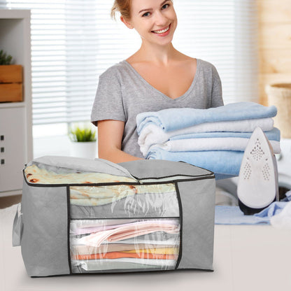 Woman holding folded clothes next to a large gray storage bag filled with more clothes.