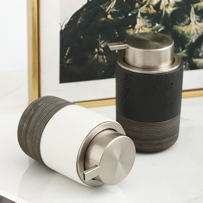 Two cylindrical containers with textured design and metallic accents on a reflective surface.