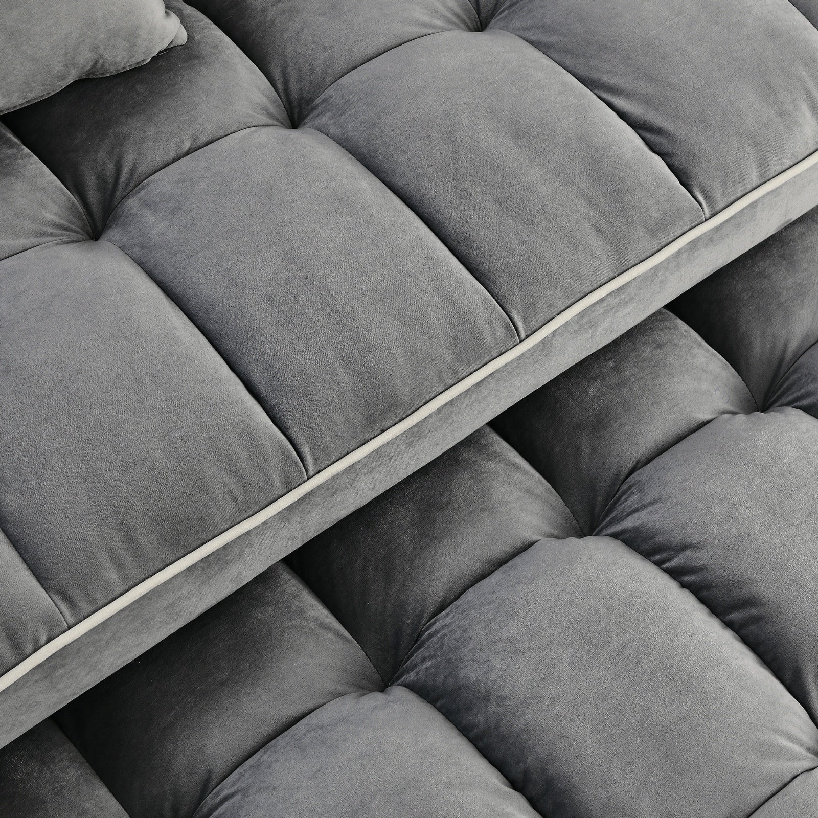 Close-up of a gray tufted sofa cushion with a visible brand logo.