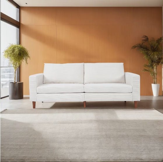 White sofa in a room with an orange wall and two potted plants.