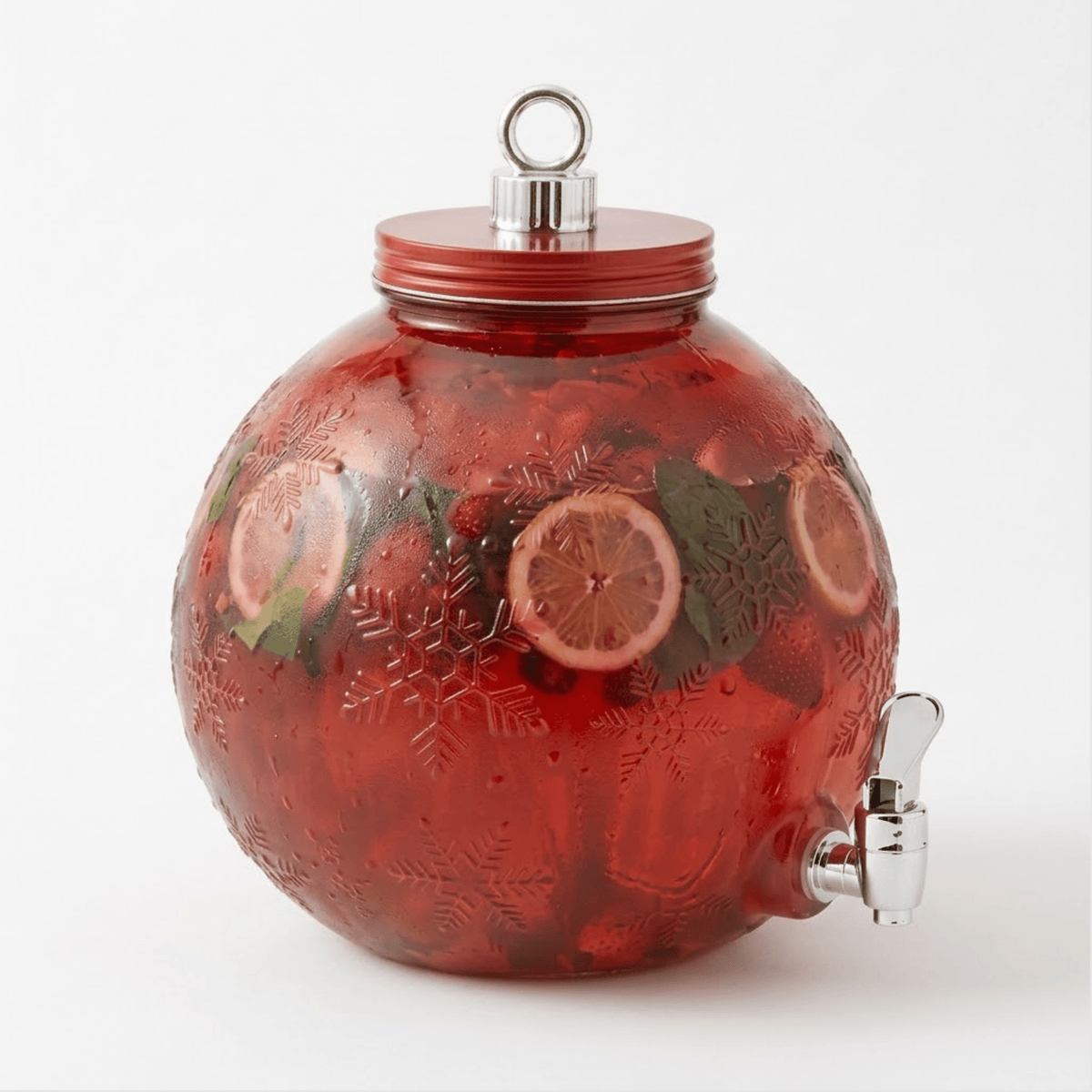 Red ornament-shaped glass beverage dispenser with embossed snowflakes, filled with a fruit drink and citrus slices