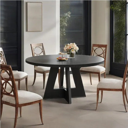 Dining room with a round black table and wooden chairs.
