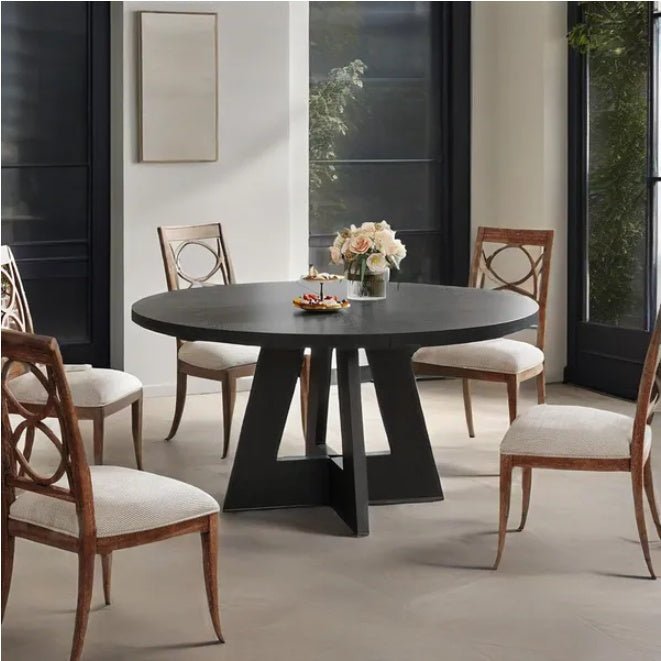 Dining room with a round black table and wooden chairs.