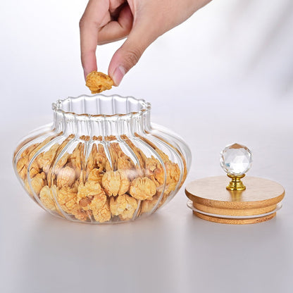 Clear glass jar with decorative lid being filled with snacks on a white background