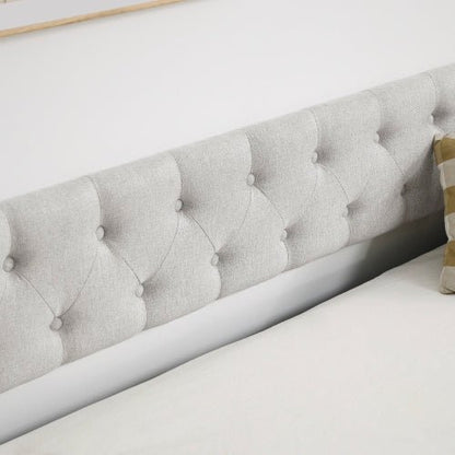 Gray tufted headboard on a bed with a white wall in the background