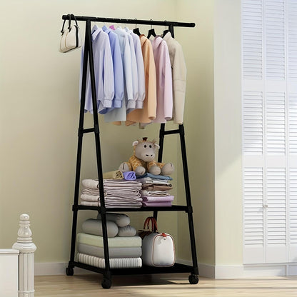Black clothing rack with clothes, folded blankets, and a teddy bear against a beige wall.