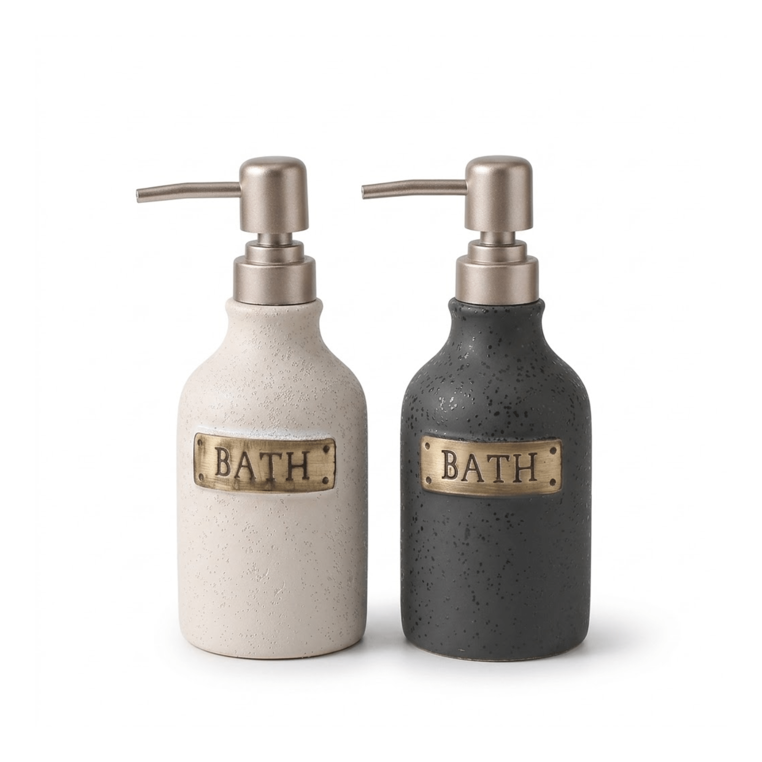 Two ceramic bath pump bottles on a white background, one in speckled cream with a brass plate reading BATH and one in speckled charcoal with a brass plate reading BATH.