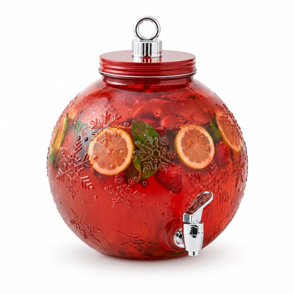 Red ornament-shaped glass beverage dispenser with embossed snowflakes, filled with a fruit drink and citrus slices