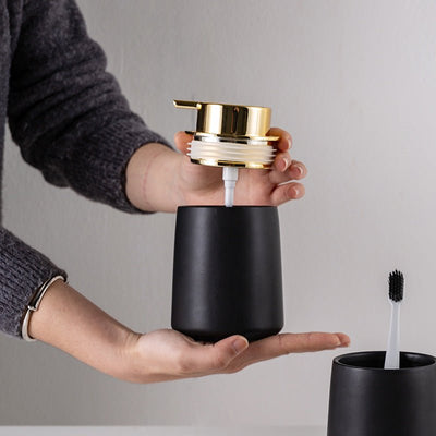 Person holding a black and gold cylindrical product against a neutral background