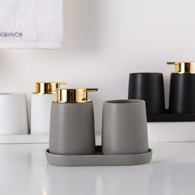 Gray bathroom accessories with gold accents on a white surface