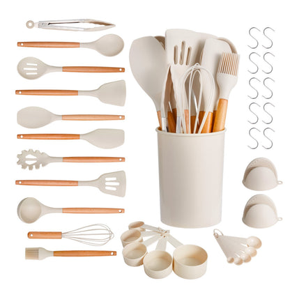Set of kitchen utensils including spatulas, whisks, and measuring cups in a white container on a white background.