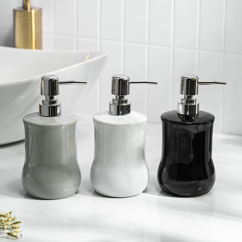 Three ceramic soap dispensers in gray, white, and black on a bathroom counter.