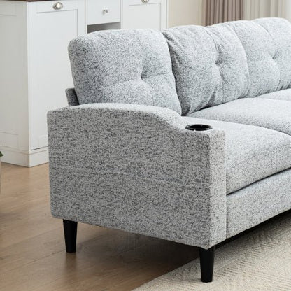 Gray upholstered sofa with cup holder in a room with white cabinets and wooden floor.