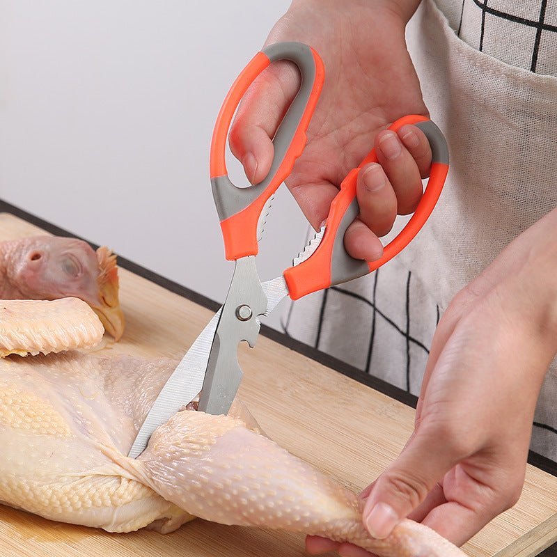 Multi-function kitchen scissors with bottle opener, cutting chicken on a wooden board.