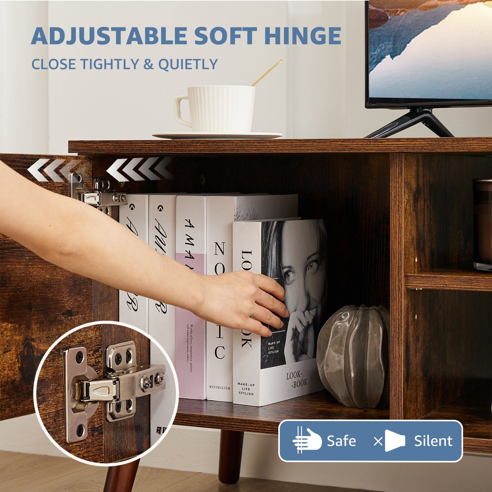 Wooden cabinet with a hand opening a shelf, showing an adjustable soft hinge, with books and a TV in the background.